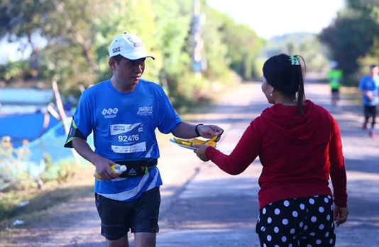 People in Quy Nhon invite runners of VnExpress Marathon 2019 to eat fruits on the road along Thi Nai lake.